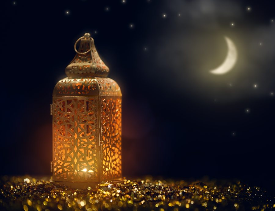 Ornamental Arabic lantern with burning candle glowing at night, representing Muslim holy month Ramadan.
